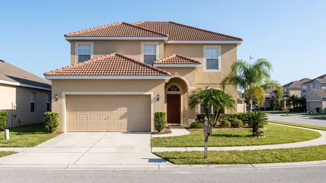 A two storey stucco house with a barrel tile roof and attached garage on a planned subdivision street, typical of suburban Orlando, Florida